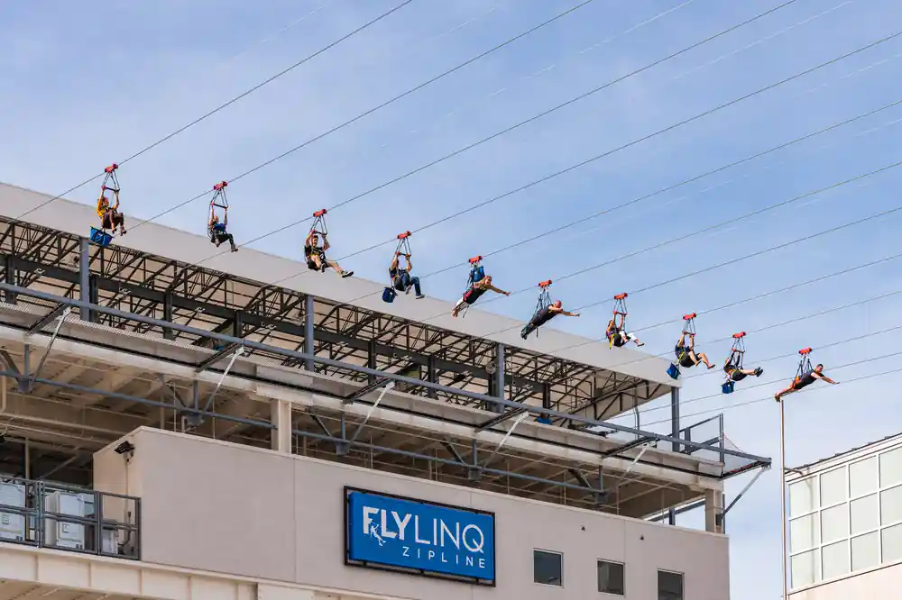 A row of riders flying flat above the zipline entrance